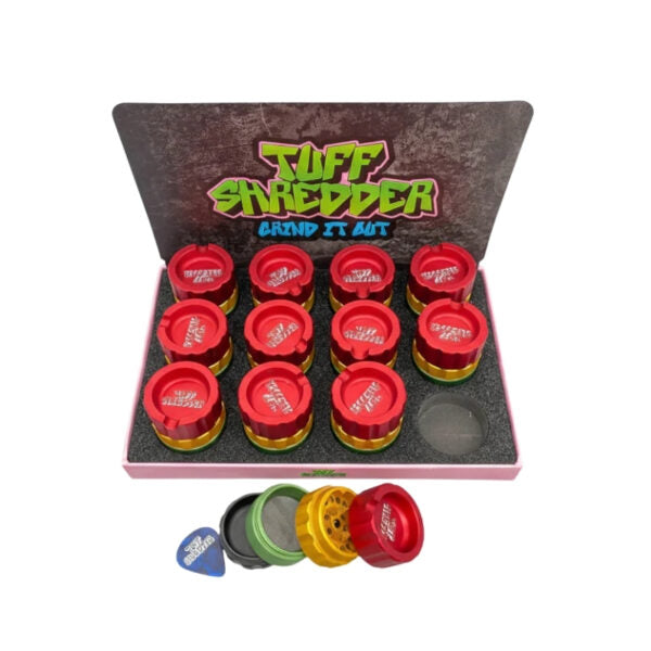 A boxed set of Tuff Shredder grinder autos, featuring a display tray with ten red and gold grinders, a few loose grinders in green, yellow, and red, and a blue paper bag, all arranged on a white background.