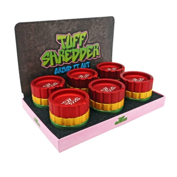 A boxed set of six Tuff Shredder grind-it-out aluminum herb grinders. The set is displayed inside its retail packaging, which features a pink base, a black foam insert, and a back panel with the green and yellow Tuff Shredder logo.