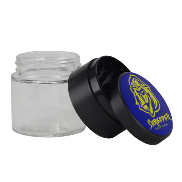 A clear glass jar with a black screw-on lid, shown with the lid removed and leaning against the jar. The lid features a blue circular label with a yellow graphic and the brand name 'SHREPPER'.