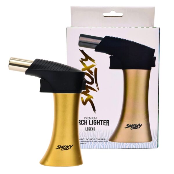 A gold and black Smoxy torch lighter shown in front of its retail packaging box on a plain white background.