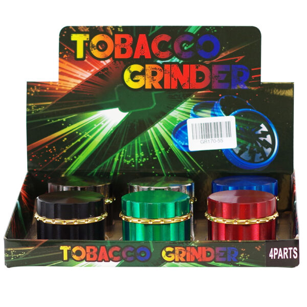 A retail display box containing four 4-part tobacco grinders in different metallic colors: black, green, red, and blue. The display features a colorful graphic backing with the words 'TOBACCO GRINDER' in rainbow lettering.