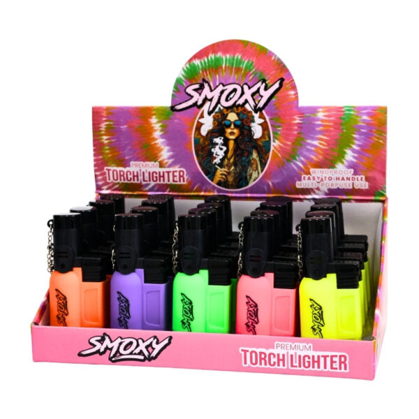 A retail display box filled with Smoxy brand torch lighters in assorted neon colors, including orange, purple, green, pink, and yellow, on a white background.