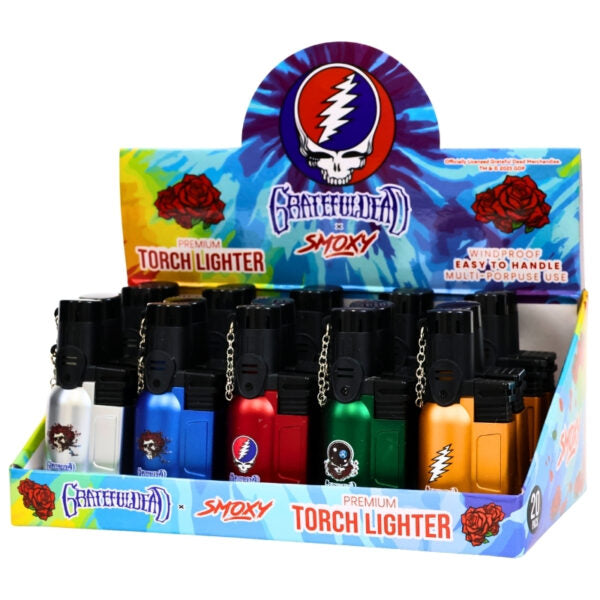 A retail display box filled with small Grateful Dead Smoky branded torch lighters in multiple colors, including silver, blue, red, green, orange, and yellow, on a white background.