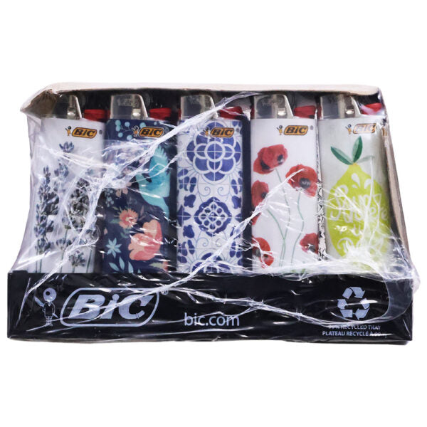A retail display box of BIC lighters wrapped in clear plastic, showing five different lighter designs: floral blue and white, blue patterned, white with red poppies, white with a green lemon illustration, and a black BIC-branded base.