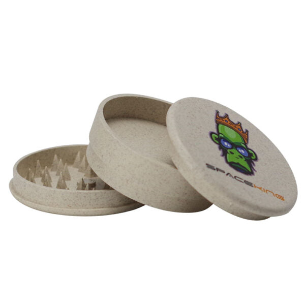 A round, eco-friendly hemp seed grinder made of natural beige fiber, shown with its lid off to reveal the sharp teeth inside. The lid features a colorful graphic of a green alien wearing a gold crown with the brand name 'SPACEKING' printed below it.