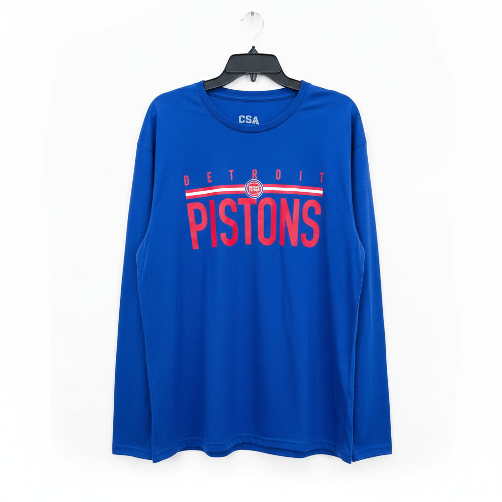 A royal blue long-sleeve Detroit Pistons t-shirt hanging on a black hanger against a wooden door background. The shirt features 'DETROIT PISTONS' printed in red across the chest with a white and red stripe design, and 'CSA' printed in white on the inside collar.