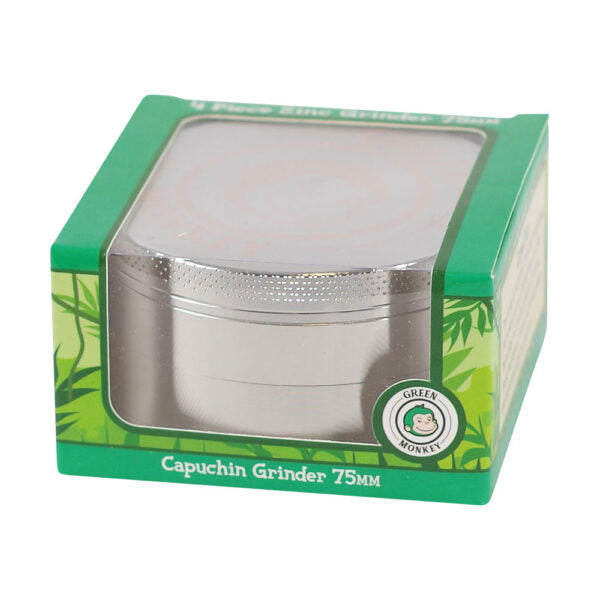 A silver metal capuchin grinder in its original green packaging box with a clear plastic window, labeled 'Capuchin Grinder 75MM' and featuring a 'Green Monkey' brand logo.