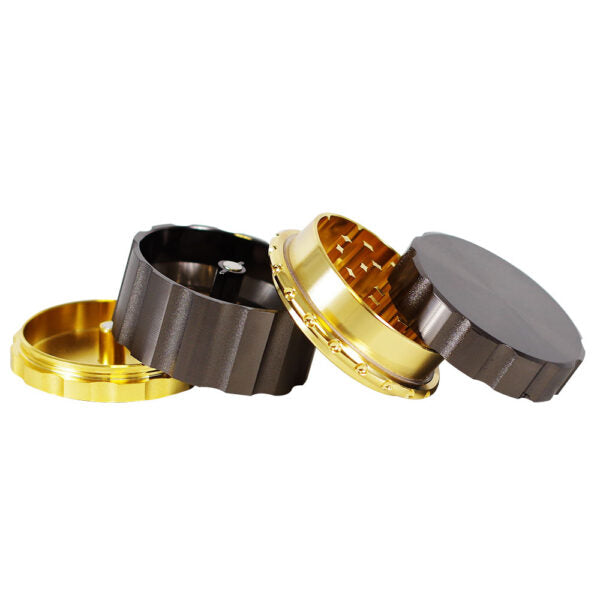 A three-piece metal herb grinder shown disassembled on a plain white background, featuring a dark gray exterior, a polished gold interior, and a gold base.