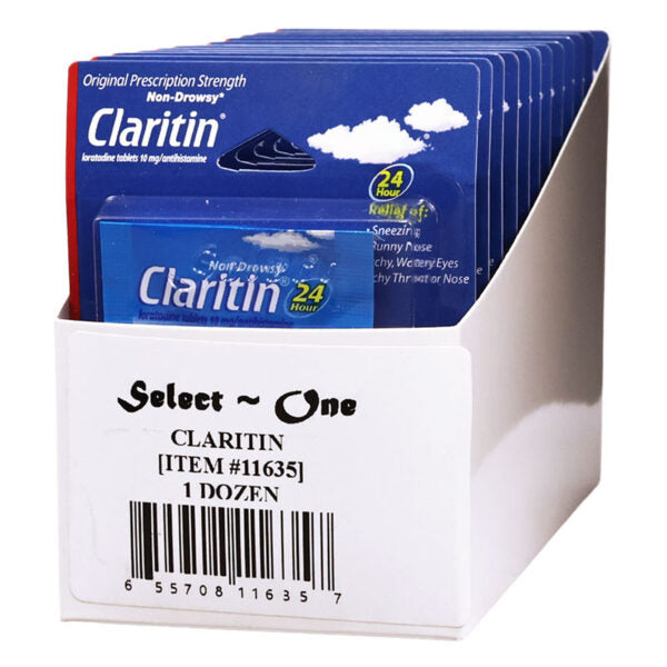 A white retail display box holding multiple blue Claritin allergy medicine packets, with the front packet clearly showing the Claritin brand and product name. The box label reads 'Select One CLARITIN [ITEM #11635] 1 DOZEN'.