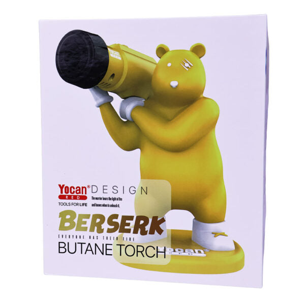 A yellow bear-shaped butane torch with a black lens-like front, shown on its product box. The box features the brand name 'Yocan DESIGN' and the product name 'BERSERK BUTANE TORCH' on a light background.