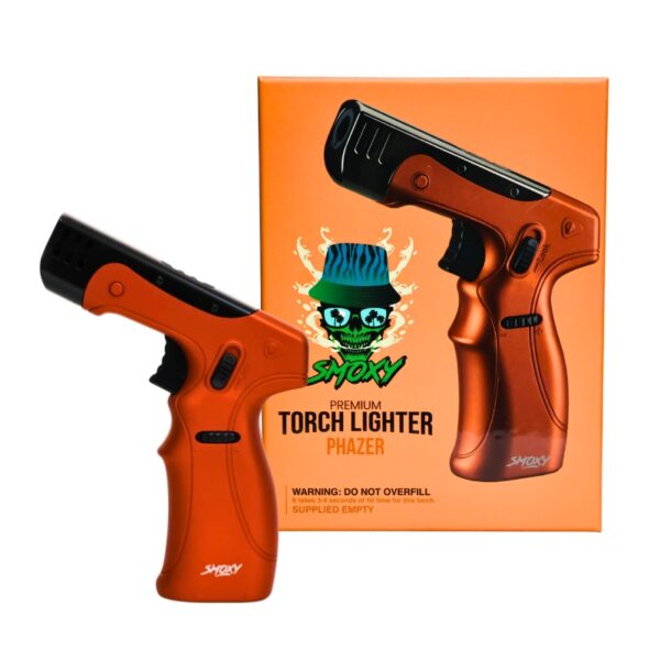 An orange and black handheld torch lighter shown in front of its matching orange retail box. The box features a cartoon skull wearing a blue hat and the text 'Smoxy' and 'Phazer'.