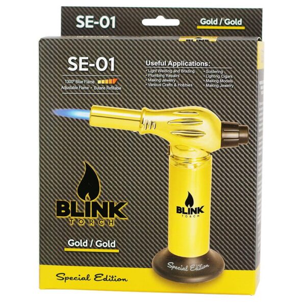 Blink Torch SE-01 Special Edition gold torch lighter in its original retail packaging, featuring a yellow torch with a blue flame graphic on a black carbon-fiber-textured box.