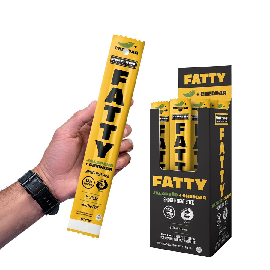 Hand holding a Fatty smoked meat stick with packaging in the background