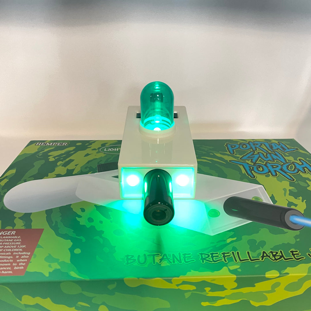 Hemper Portal Gun jet torch with glowing green LED lights and a plasma core, resting on its branded packaging.