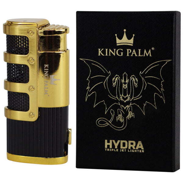 King Palm Hydra triple jet lighter in a black and gold finish, shown next to its black packaging box with gold lettering.