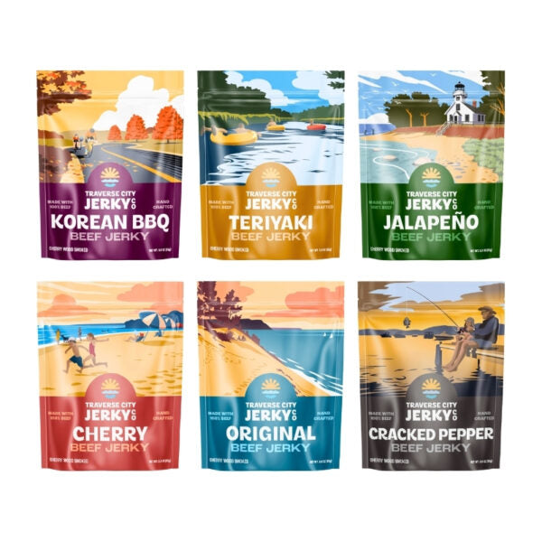Six stand-up pouches of Traverse City Jerky beef jerky in assorted flavors, arranged in two rows on a white background. The flavors shown are Korean BBQ, Teriyaki, Jalapeño, Cherry, Original, and Cracked Pepper, each with a colorful illustrated package design.