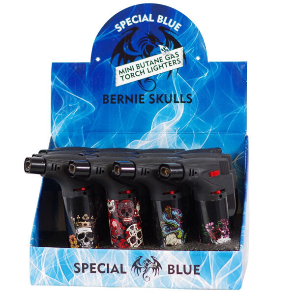 A retail display box containing four mini butane gas torch lighters themed with 'Bernie Skulls' and 'Special Blue'. The lighters feature black bodies with various colorful skull and graphic designs on their transparent fuel tanks.